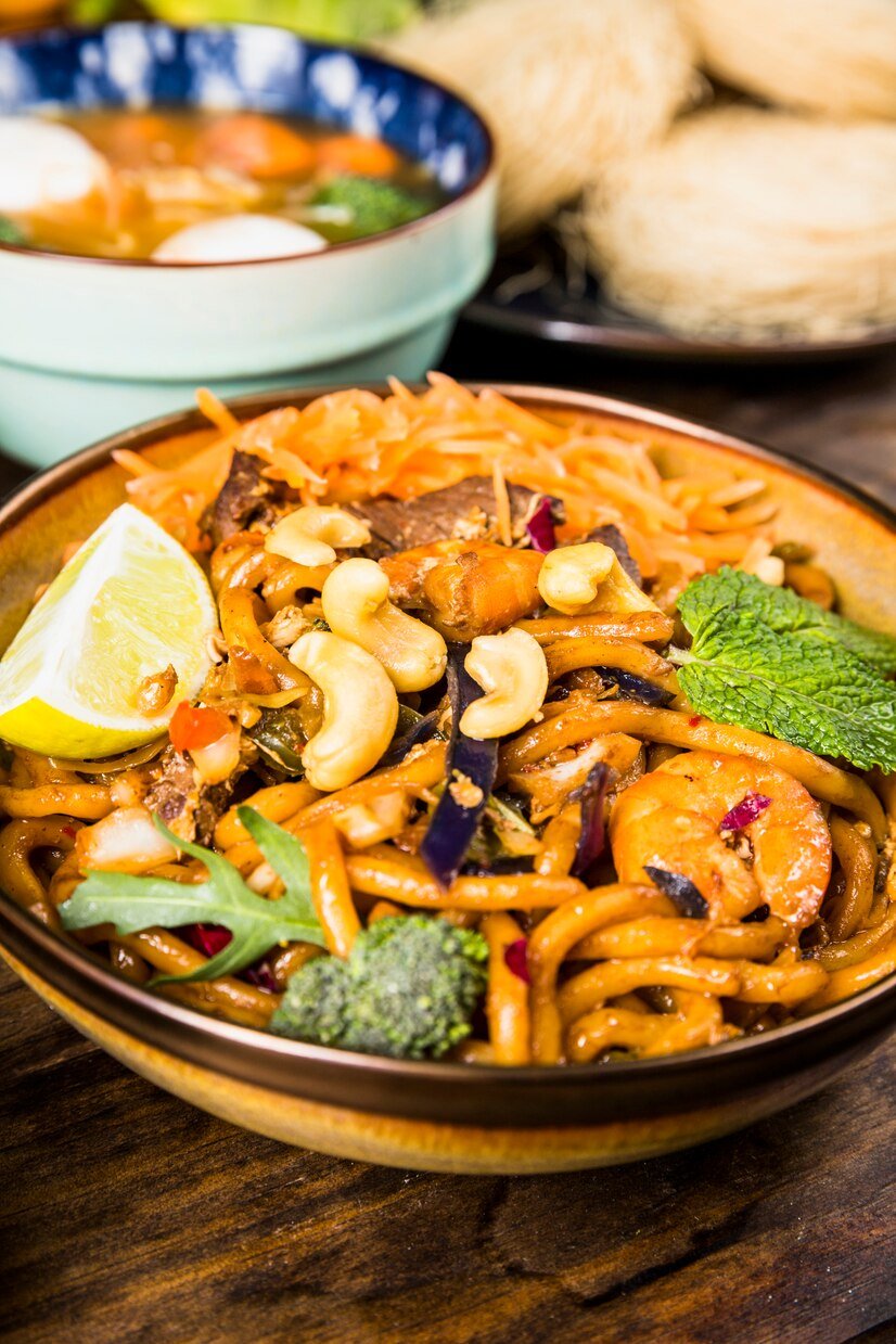 tasty-thai-udon-noodles-with-beef-broccoli-mint-nuts-lemon-bowl-wooden-table_23-2148093292