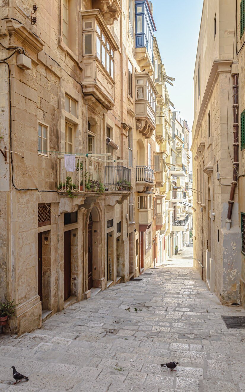 vertical-shot-alley-old-buildings-sunlight-valletta-malta_181624-49631