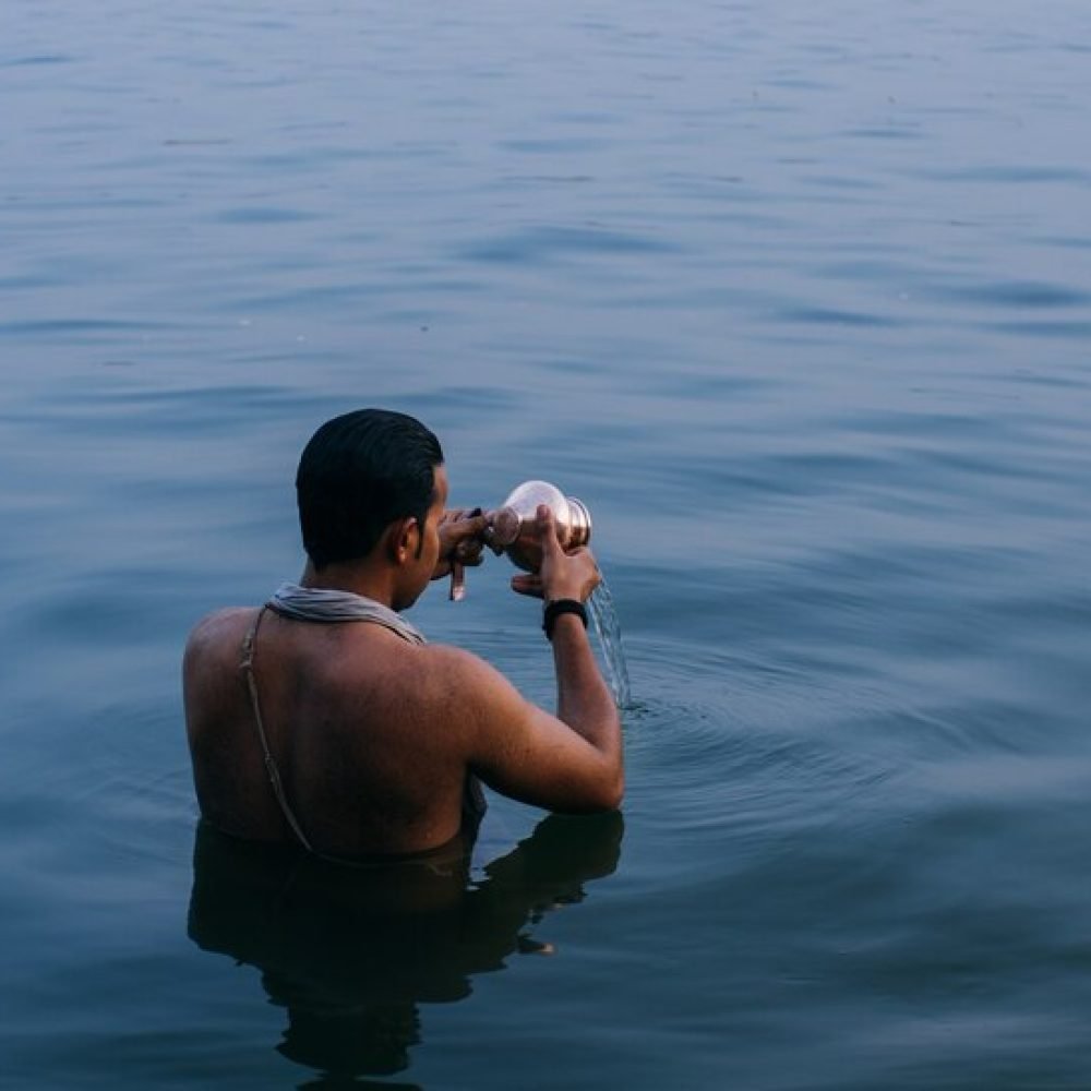 person-standing-water-while-emptying-copper-bowl-india_181624-12542